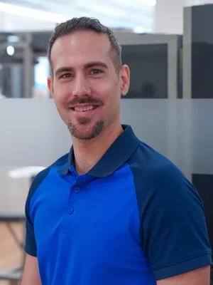 Reto Mosimann, Instruktor im Kieser Bern, lächelnd im blauen Kieser-Poloshirt